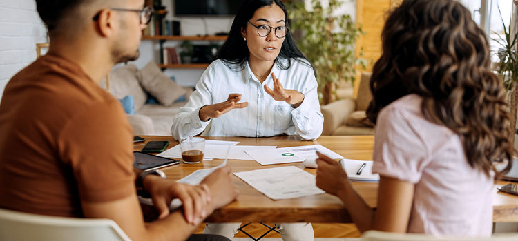 a professional woman consults with two clients in an office