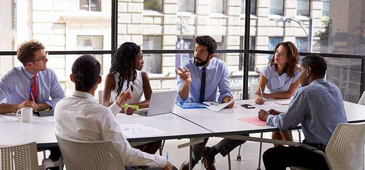 a leader talking with his team at a table in a conference room