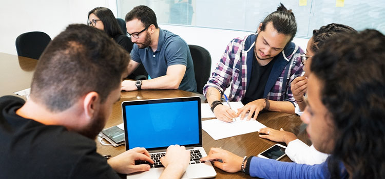 students work together on laptops and paper at a table