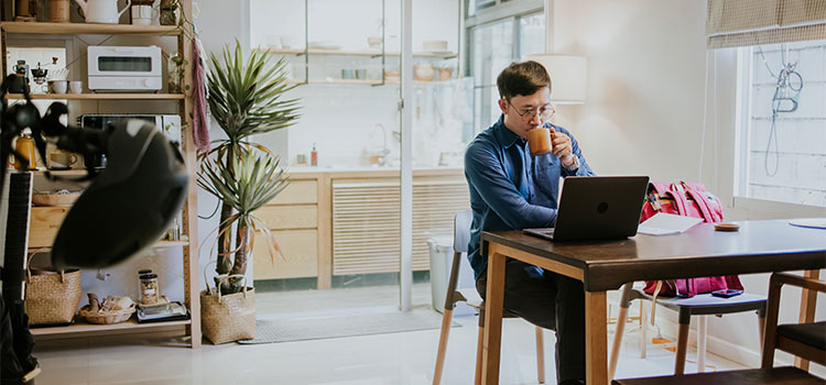 a man does research on his laptop at his kitchen table