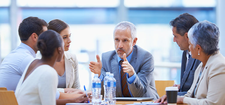 A man explains an issue to other professionals sitting around a table