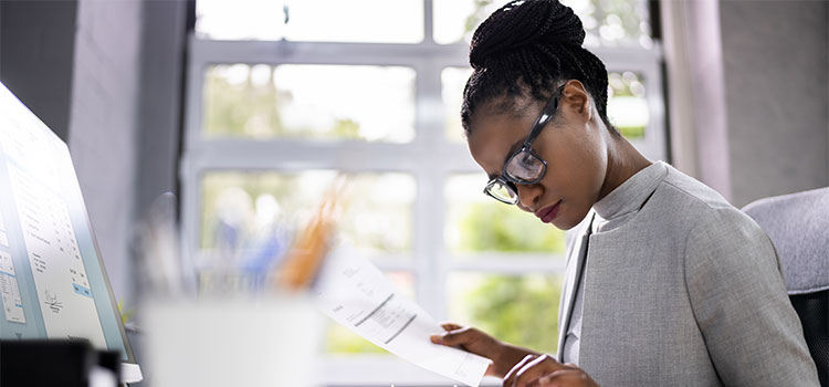 a woman goes over numbers with a calculator as she works at a desk
