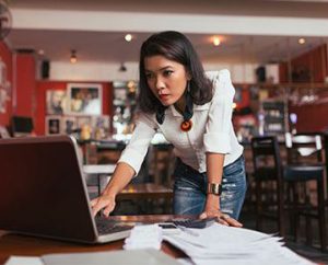 woman enters receipts into laptop in her restaurant