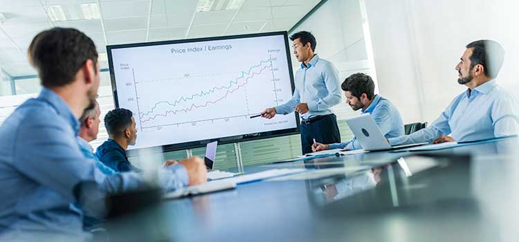 male financial analyst presenting report to men at conference room table