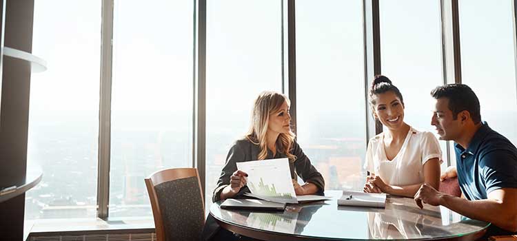 three people sitting around conference room table discussing clients