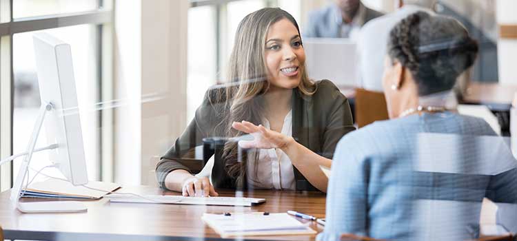 two women discussing finances at desk in office