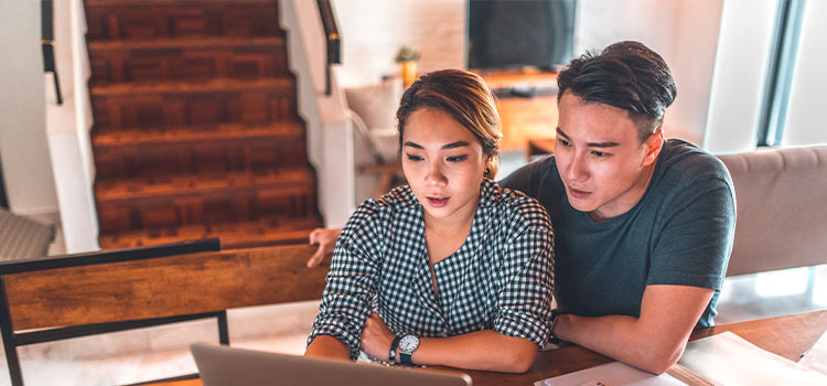 A woman at home reads information online as a man looks on
