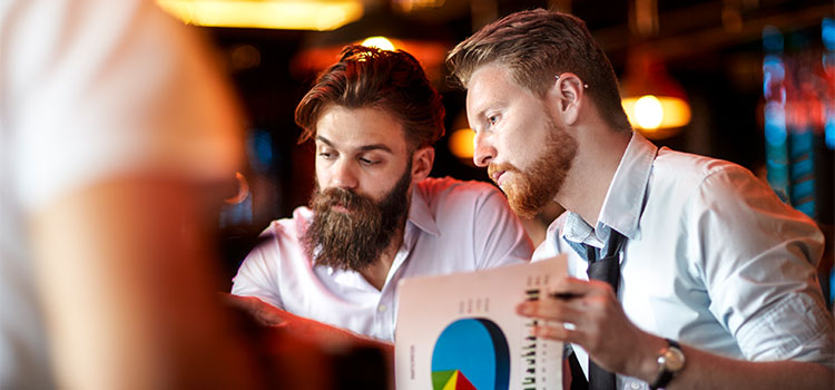 Two men in an office look over data charts