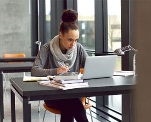woman in scarf studies on laptop in library