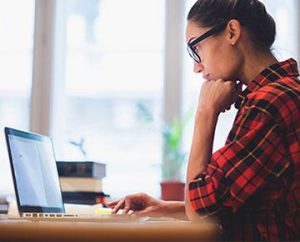 woman ponders information on laptop
