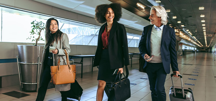 Three colleagues walk through an airport to catch a flight