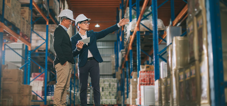 Two men discuss merchandise in a warehouse