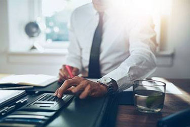 man in tie working on calculator to balance investment