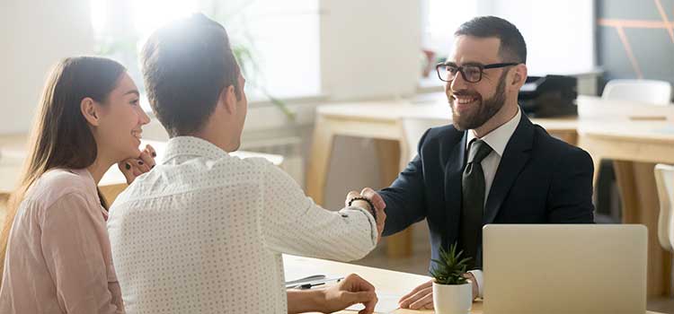 loan officer shakes hands with couple securing loan