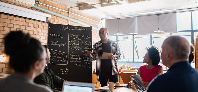 Man explains information on a board to his team