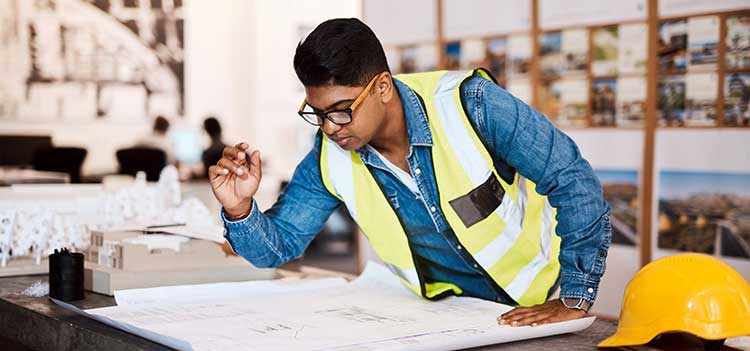 man in safety vest looking at construction plans