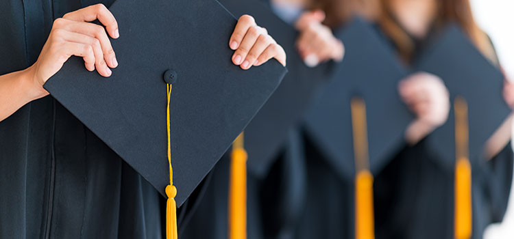 row of mortar boards in hands of graduates