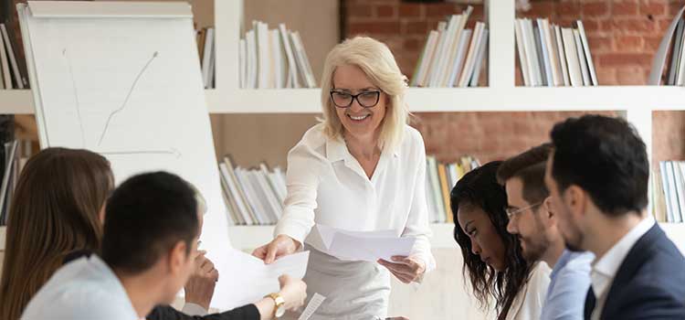 woman leading meeting handing out papers to attendees