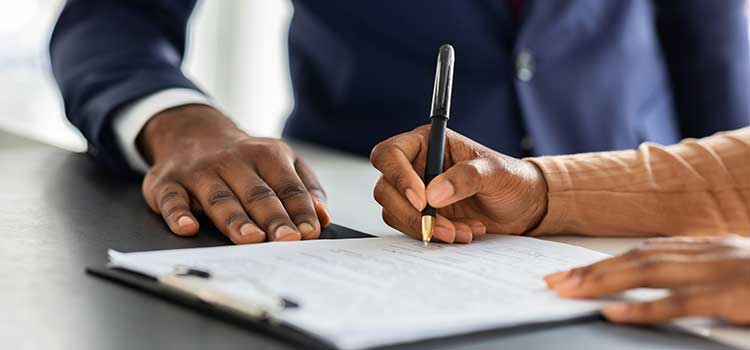 close up of hands filling out paperwork on clipboard