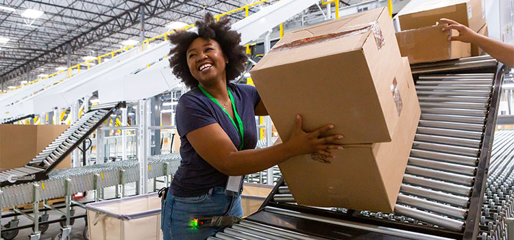a woman places boxes on a conveyor belt in a warehouse