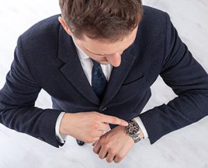 man in suit checks watch for time