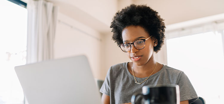 A woman reads on her laptop.