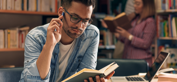 male student reading in the library